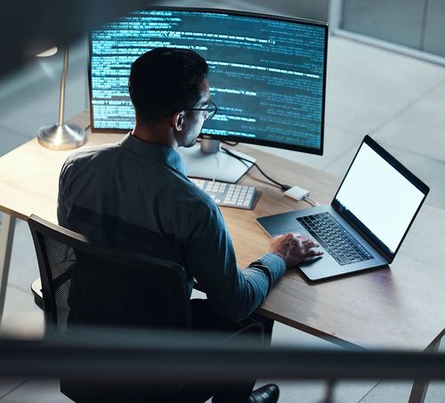 A man sitting at a desk using a laptop computer.