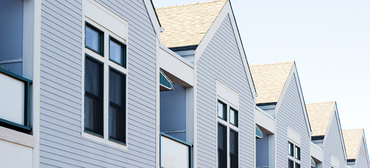 Row of pale blue modern townhouses with gabled roofs and multiple windows.