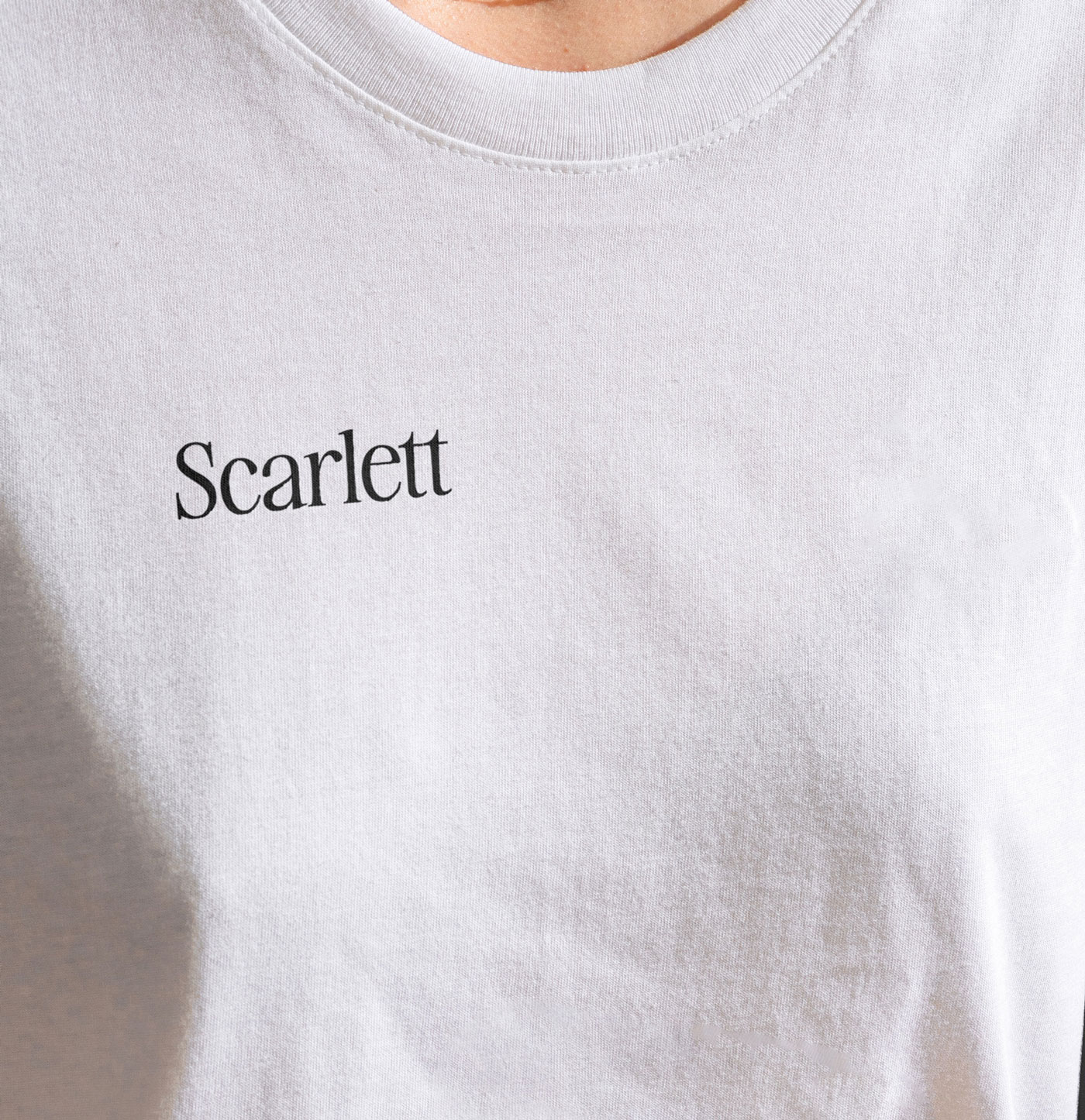 Close up of a womans t-shirt that has DTF printing on it that says Scarlett
