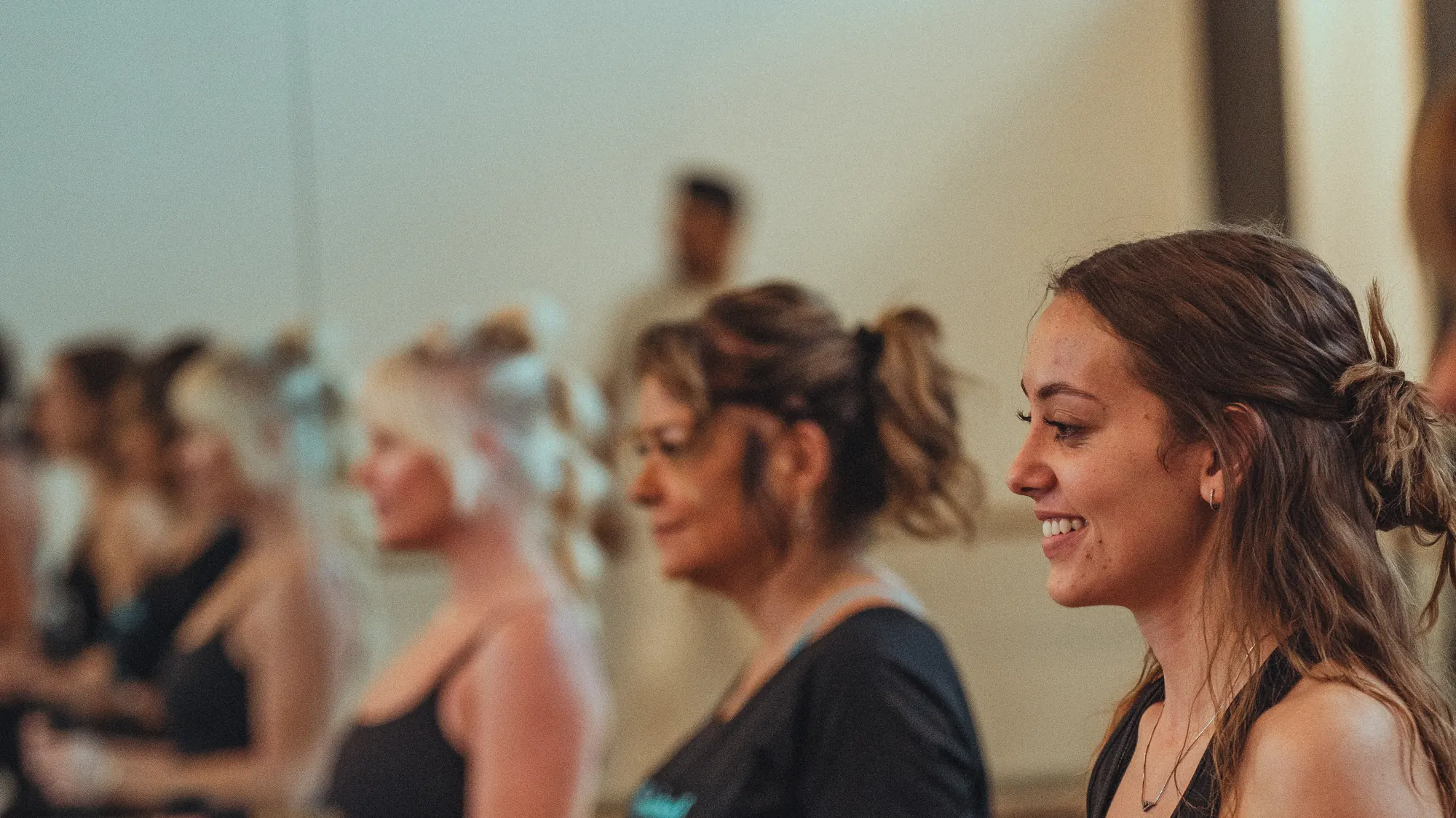 Smiling members holding light weights during a barre class at a boutique studio