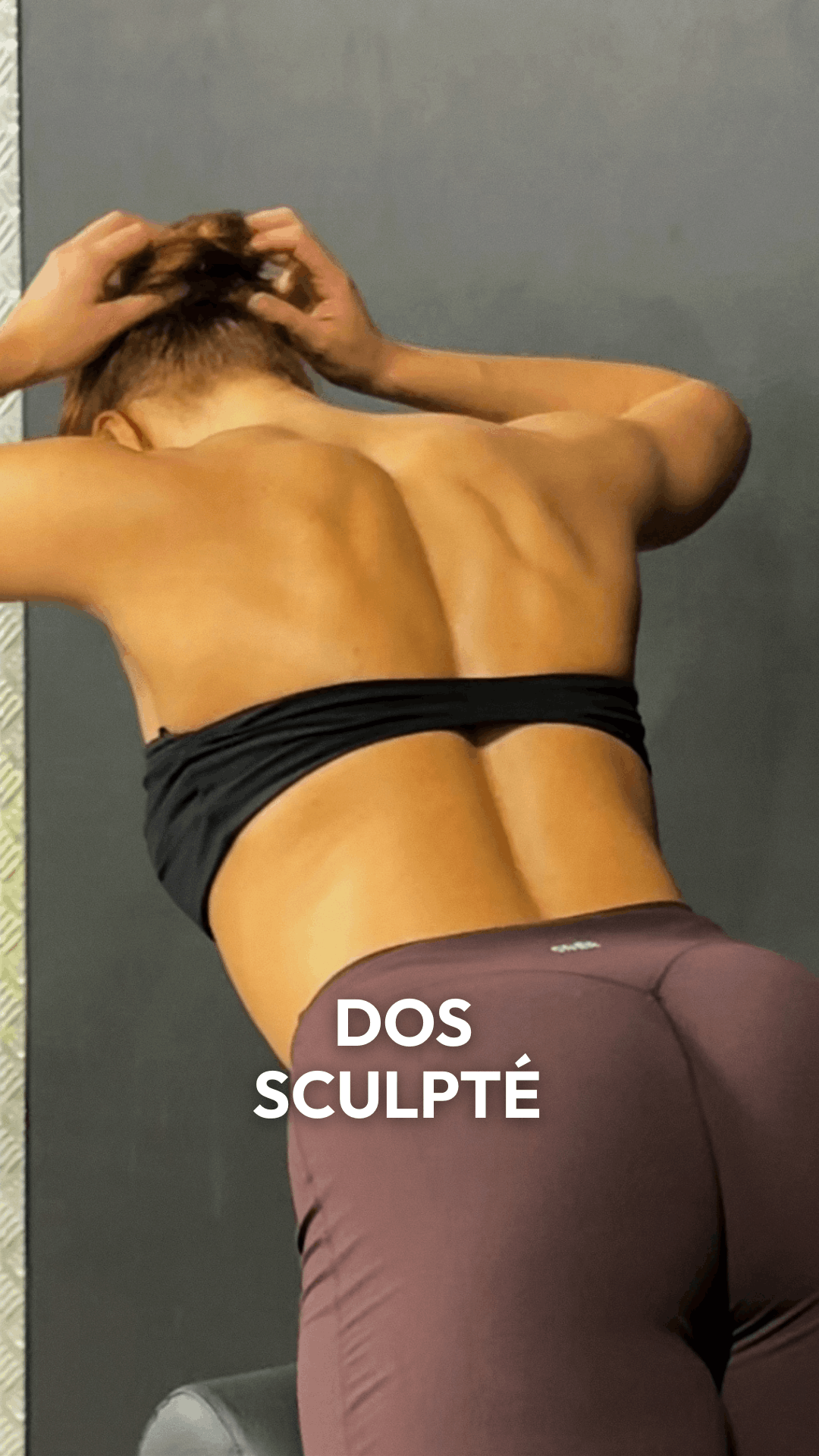 Person with a sculpted back in a workout pose wearing a black top and maroon leggings.