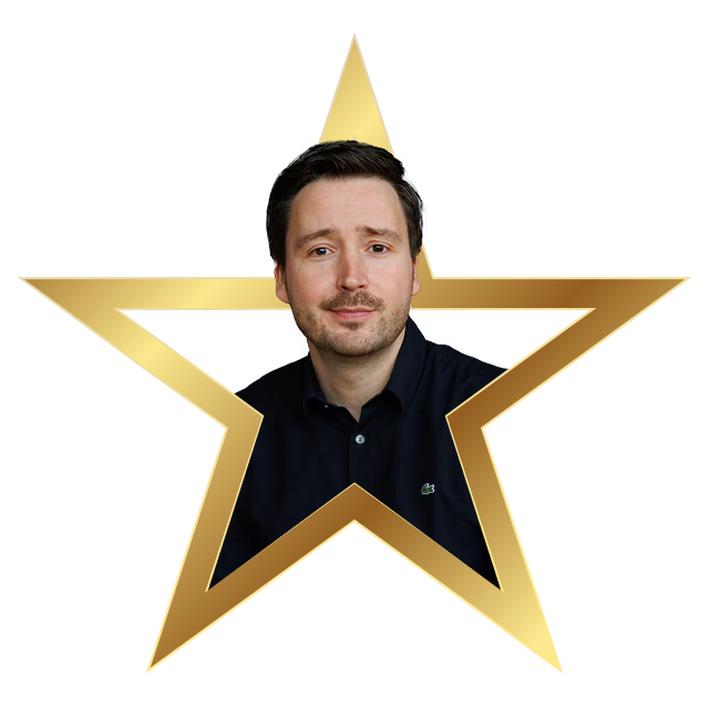 Man with short dark hair and light facial hair wearing a black shirt inside a gold star frame.