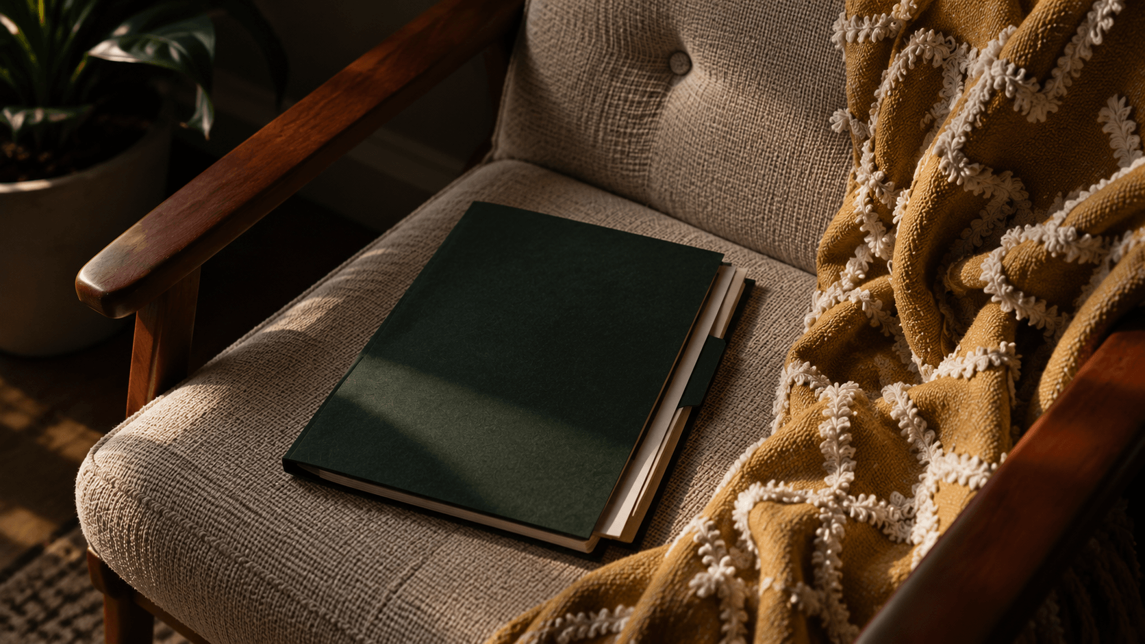 Dark green document folder resting on a linen armchair beside a mustard throw, lit by late afternoon sun.