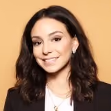 Smiling woman with shoulder-length dark hair wearing a black blazer and white top.