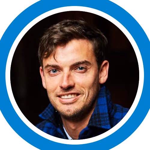 Smiling young man with blue eyes and short brown hair wearing a blue plaid shirt.
