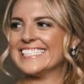 Close-up of a smiling woman with blonde hair and sparkling earrings.