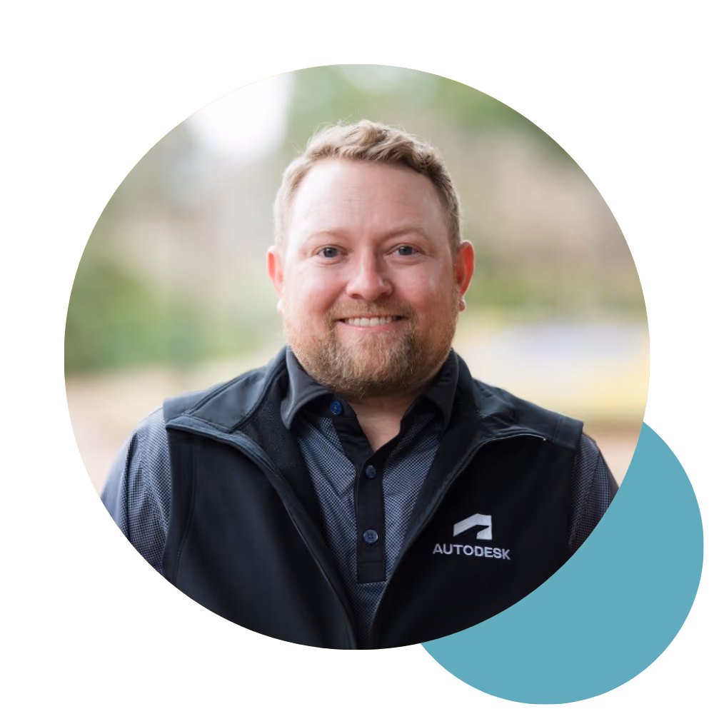 Smiling man with beard wearing black Autodesk vest, blurred outdoor background in circular crop.