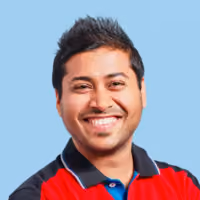 Smiling man with short black hair wearing a red and black polo shirt against light blue background.