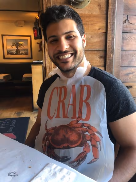 Smiling man wearing a bib with a large red crab and the word CRAB on it.