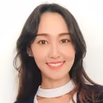 Portrait of a young woman with long dark hair smiling against a plain white background.