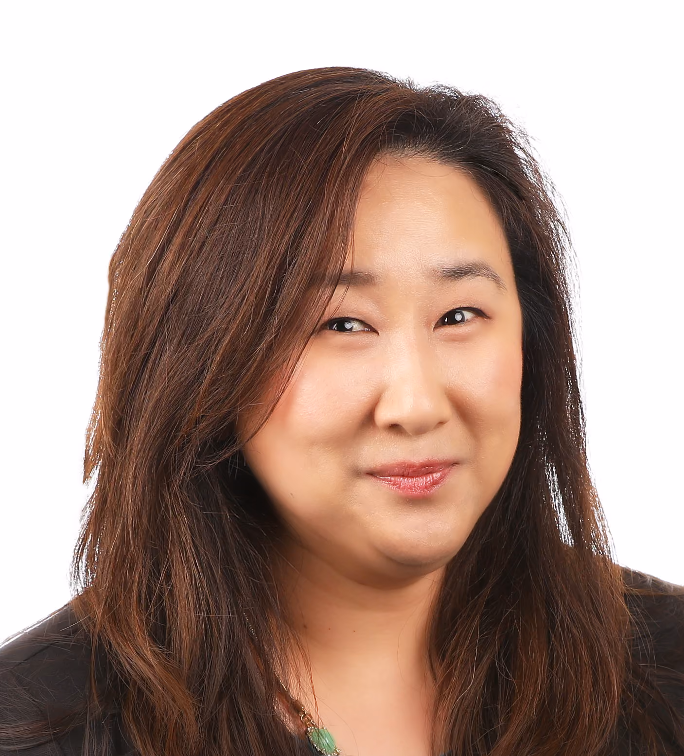 Smiling woman with long dark brown hair wearing a black top and green necklace on white background.