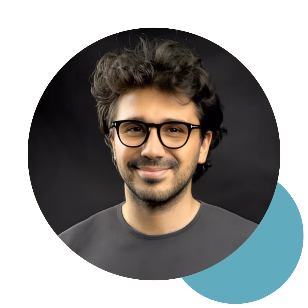 Man with curly dark hair and glasses smiling against a dark background inside a circle.