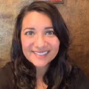 Smiling woman with dark hair posing against a wooden background.