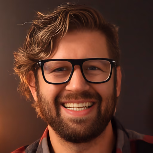 Smiling man with glasses and wavy hair against a dark brown background.