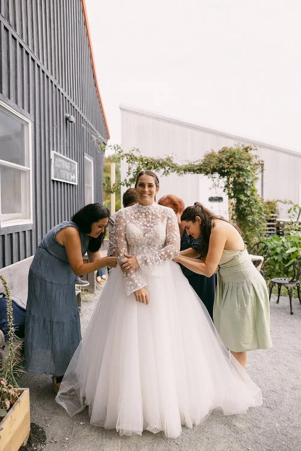 Bride getting ready in a lace wedding dress with bridesmaids helping before an intimate wedding.