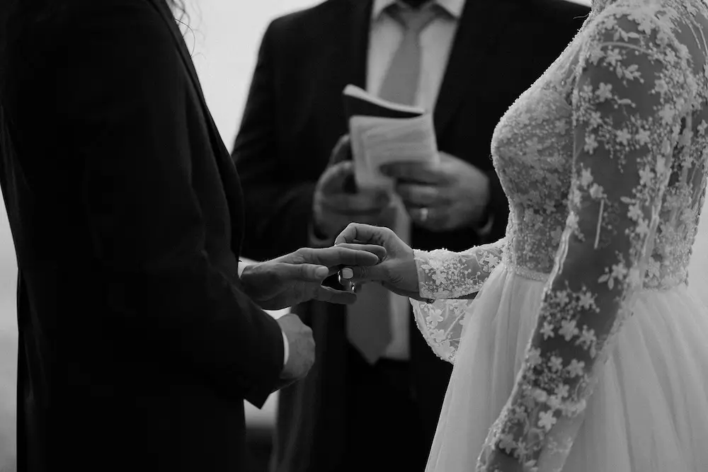 Close-up of two people exchanging wedding rings during a ceremony.