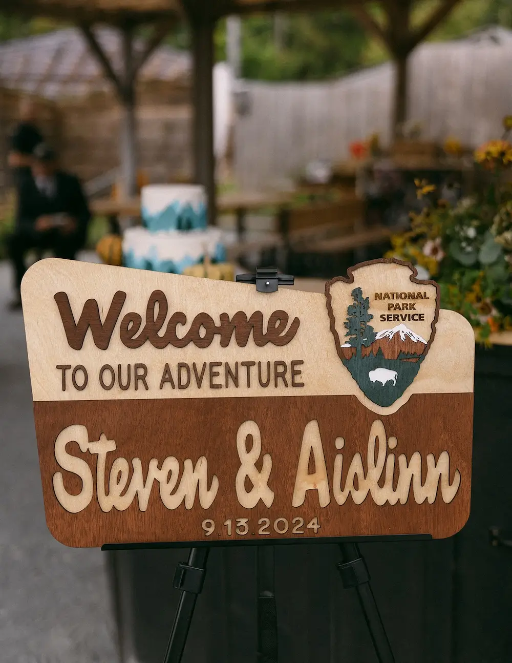 Wooden wedding welcome sign on an easel with carved lettering and a National Park–style design.