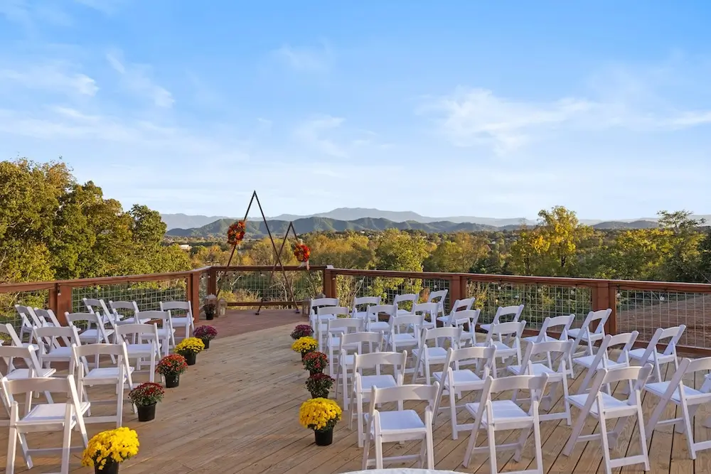 Outdoor mountain-view ceremony setup at The Grand Haven small wedding venue in Tennessee with white chairs and fall floral aisle décor.