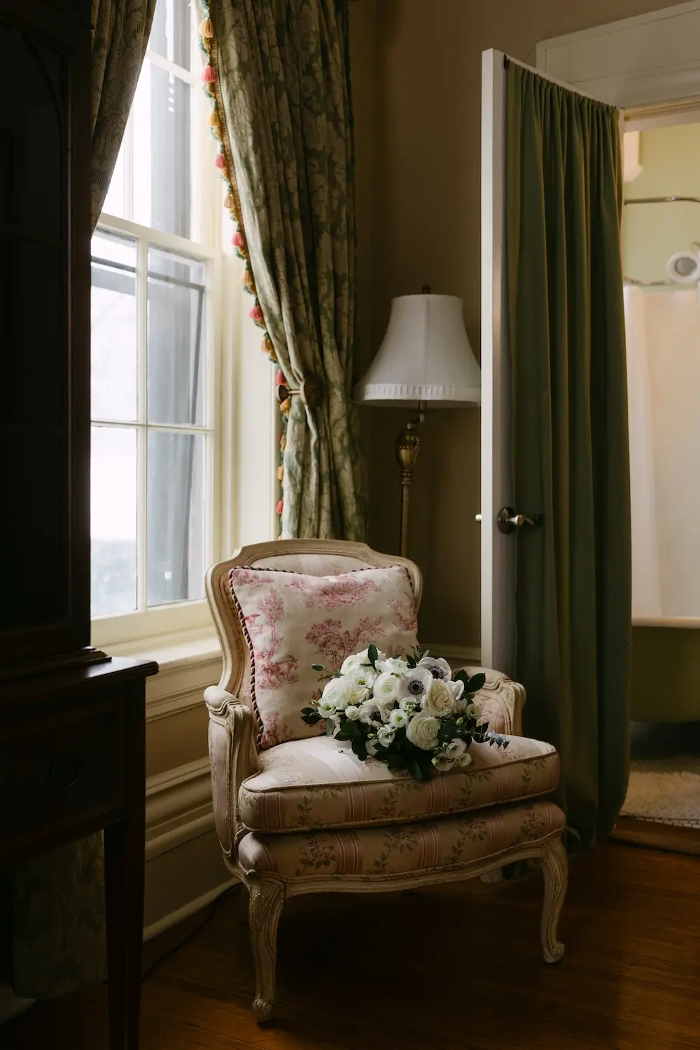 Vintage armchair by a sunlit window with a white floral bouquet