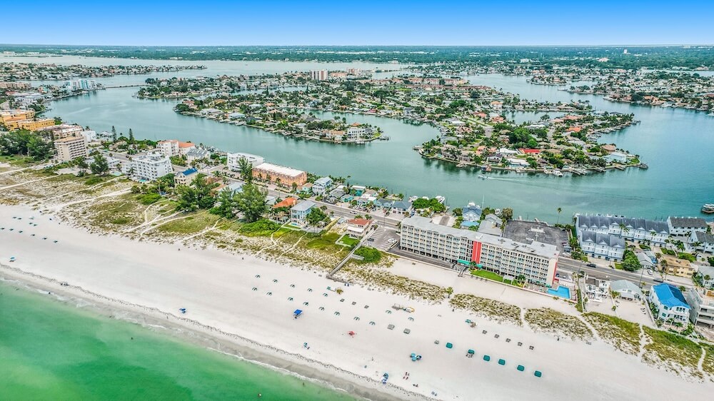 Aerial panorama of Treasure Island Florida, white sand Gulf beach lined with low coastal homes, intracoastal waterway and islands beyond