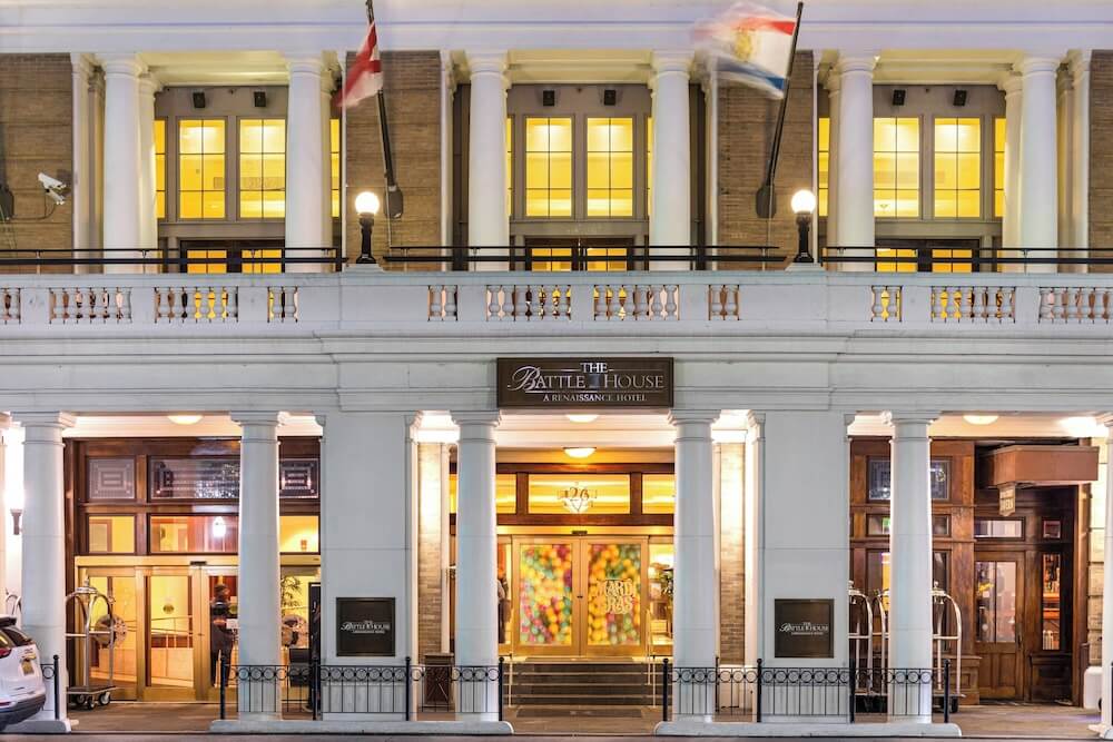 Beaux-Arts Alabama micro wedding venue at night, tall white columns, balustrade balcony, illuminated Palladian windows, two flags flying overhead