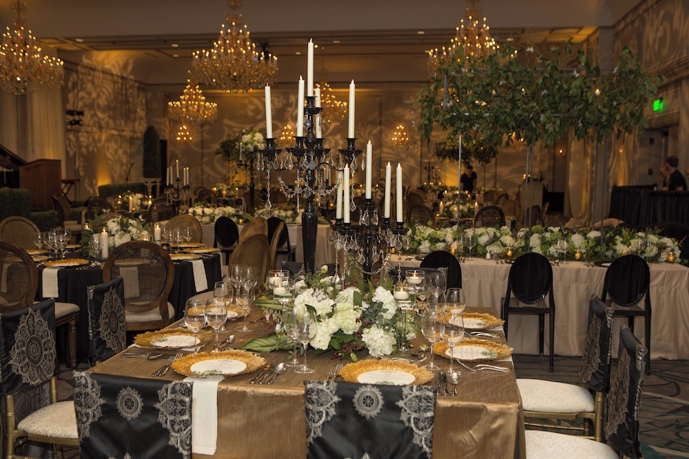 Opulent Alabama micro wedding ballroom with tall black candelabras and white tapers, hydrangea florals, gold chargers, chandeliers, damask projections