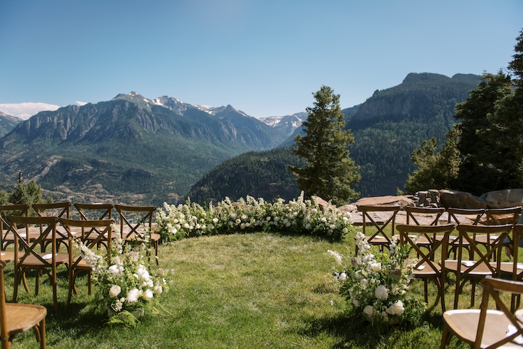 Stone-and-timber ranch wedding venue with a wide outdoor ceremony lawn under open sky
