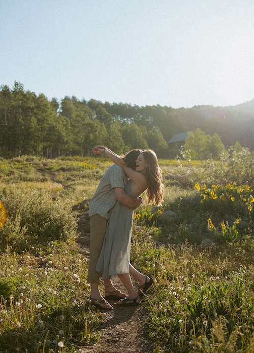 Couple in cozy sweaters with snowy Crested Butte mountain peaks behind them, dusted in alpenglow