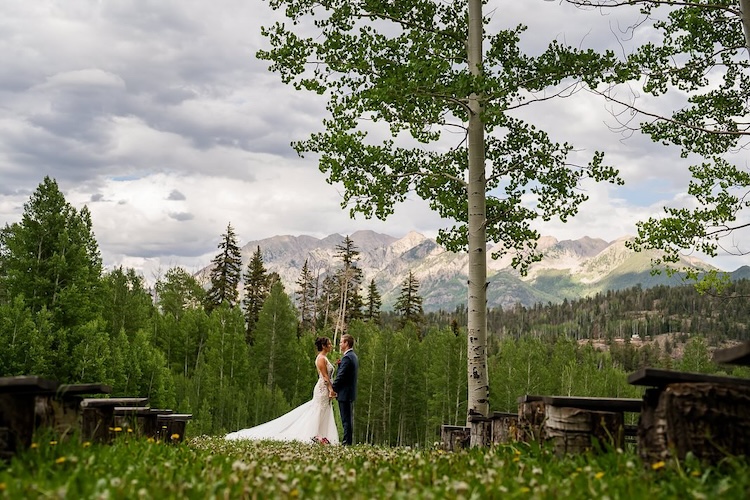 Couple stands together on a mountain ridge during their wedding weekend, with valley views unfurling behind them