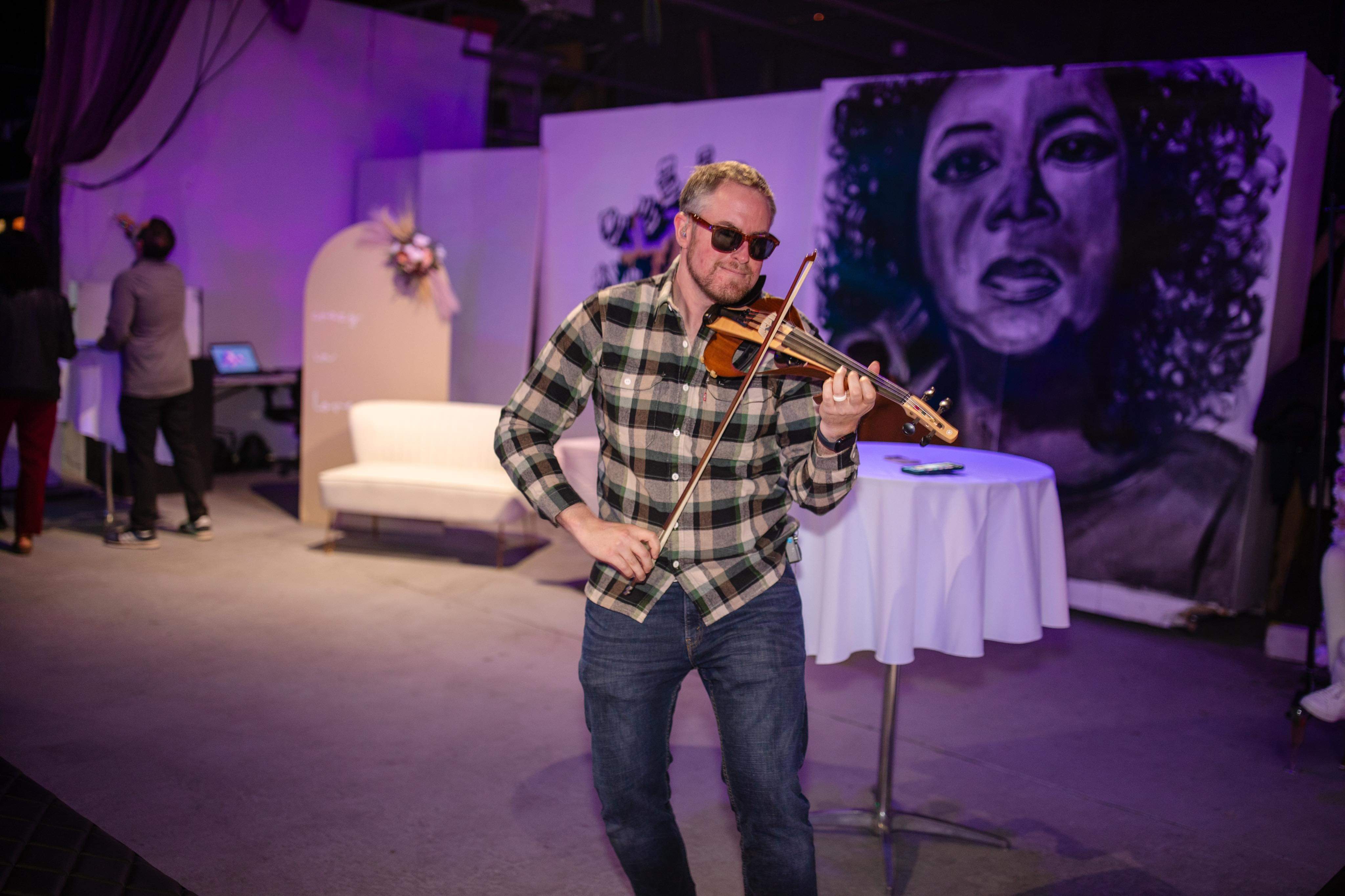 Electric violinist performing solo at an intimate event, lit by warm ambient light