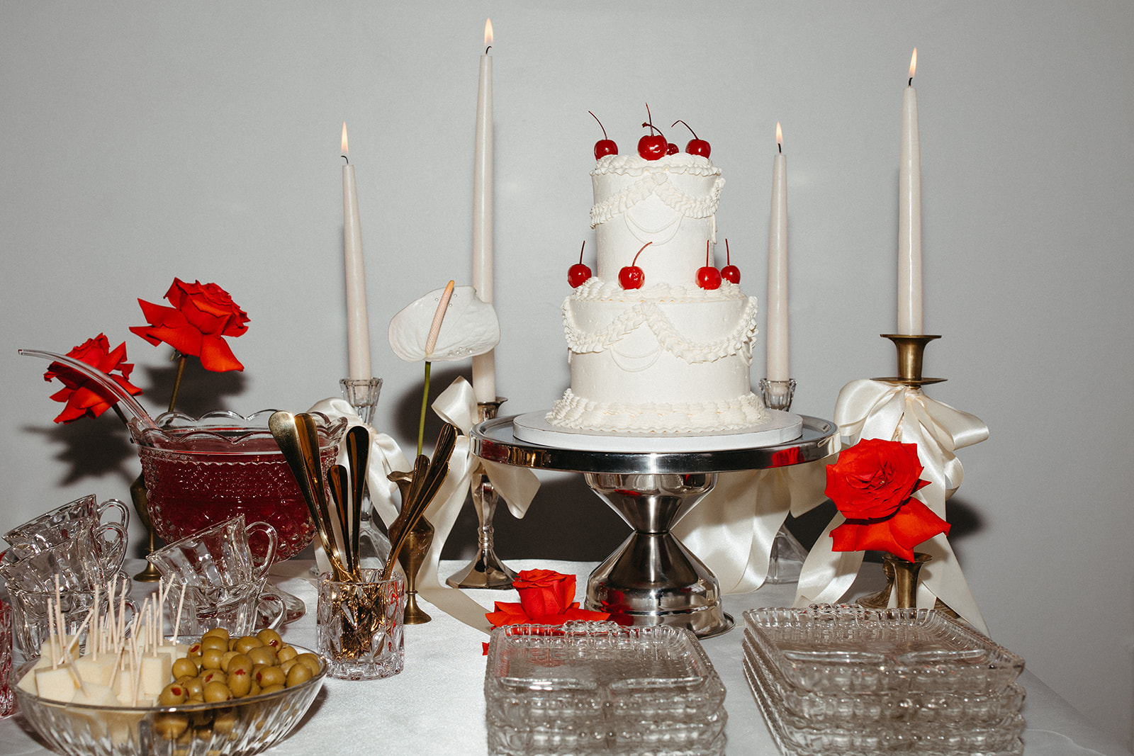 Small white wedding cake topped with fresh cherries on a clean cake stand at a micro wedding reception