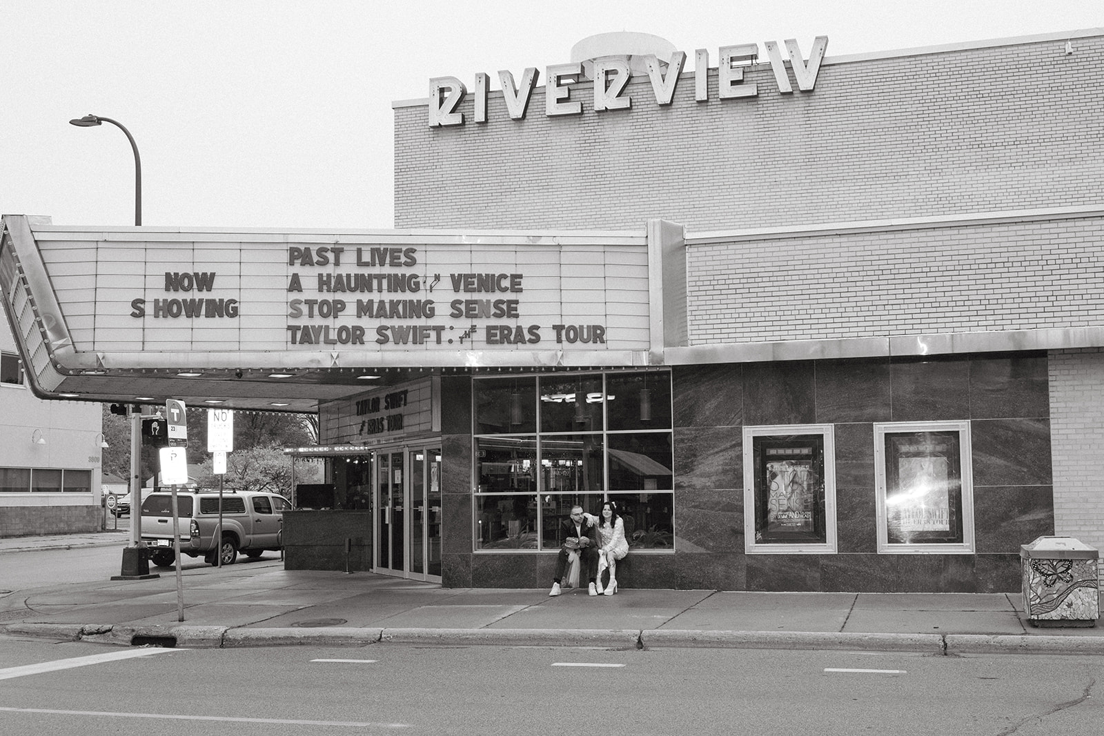 Couple poses outside the vintage bowling alley they used for their micro wedding reception, mid-century signage above