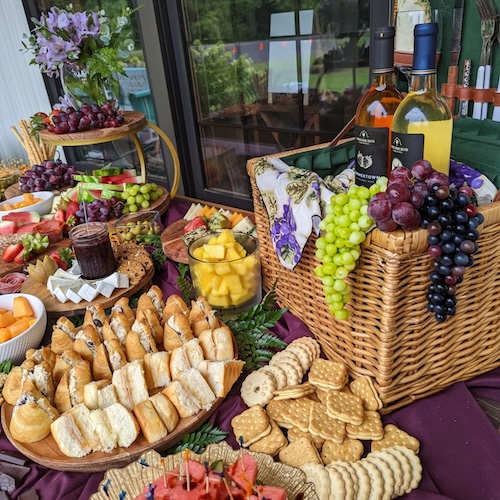 Spread of sandwiches, fruit, and snack platters arranged on a wooden surface for a small wedding meal