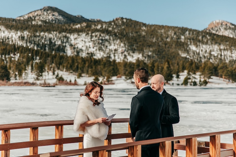 Couple exchanges vows in front of a frozen, snow covered lake at their winter elopement