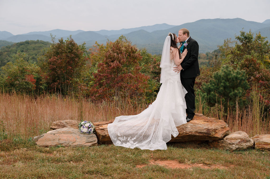 A couple stands on a stone balcony at a North Carolina mountain wedding venue in autumn