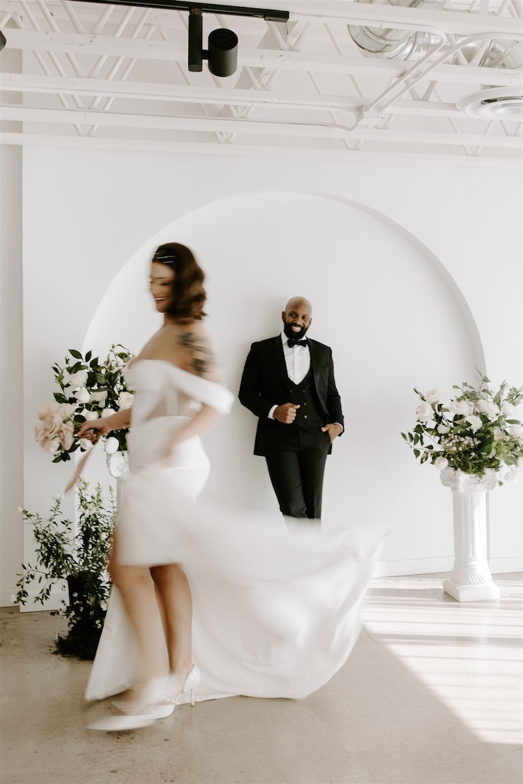 A groom smiles at his wife twirling in her wedding dress
