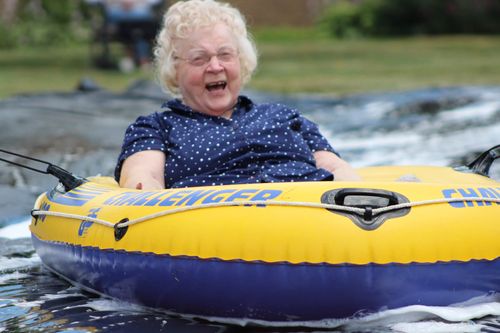 A senior citizen having the time of her life on a slip n slide inner tube.