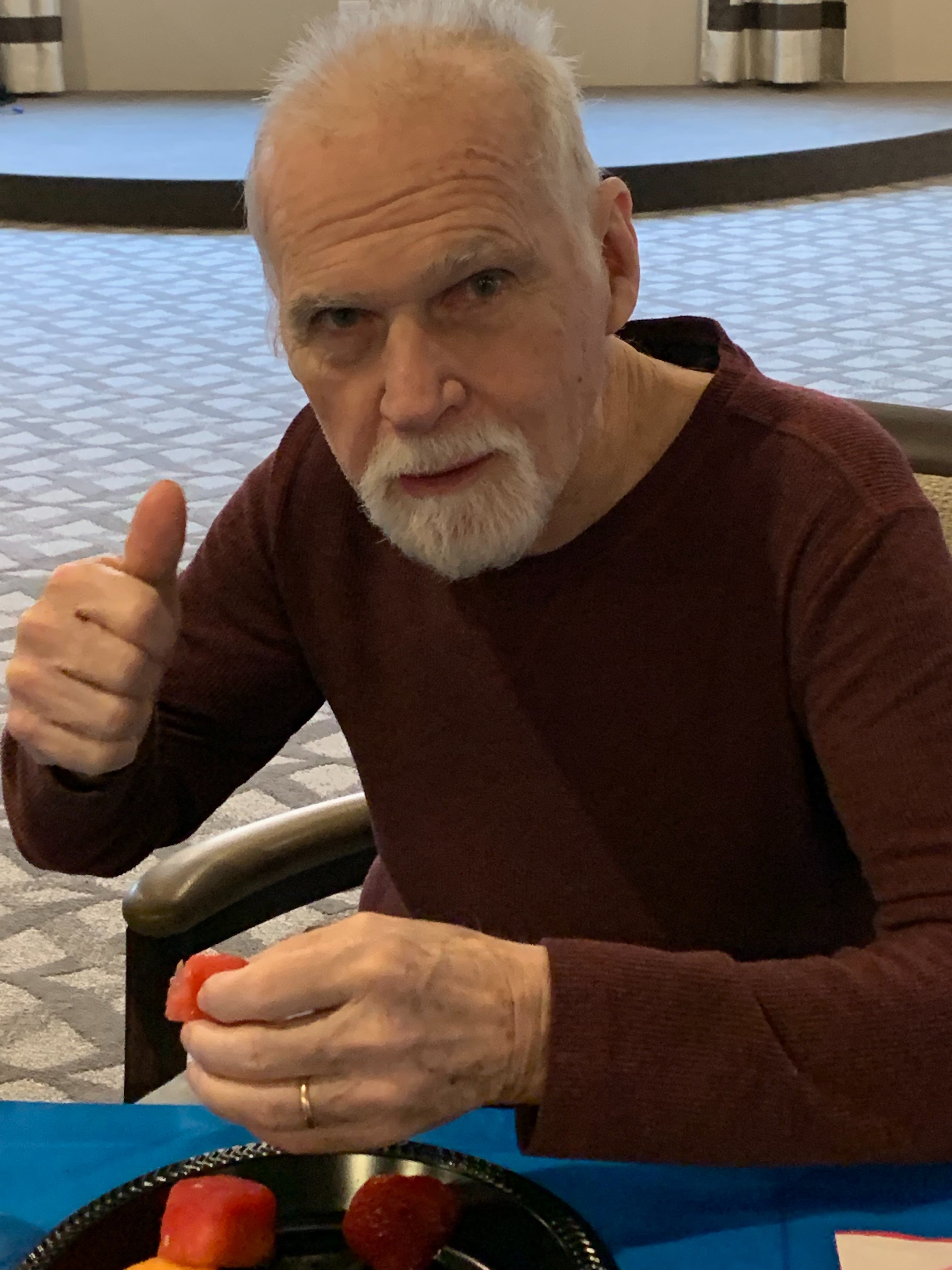 A senior man enjoying a plate of fruit.