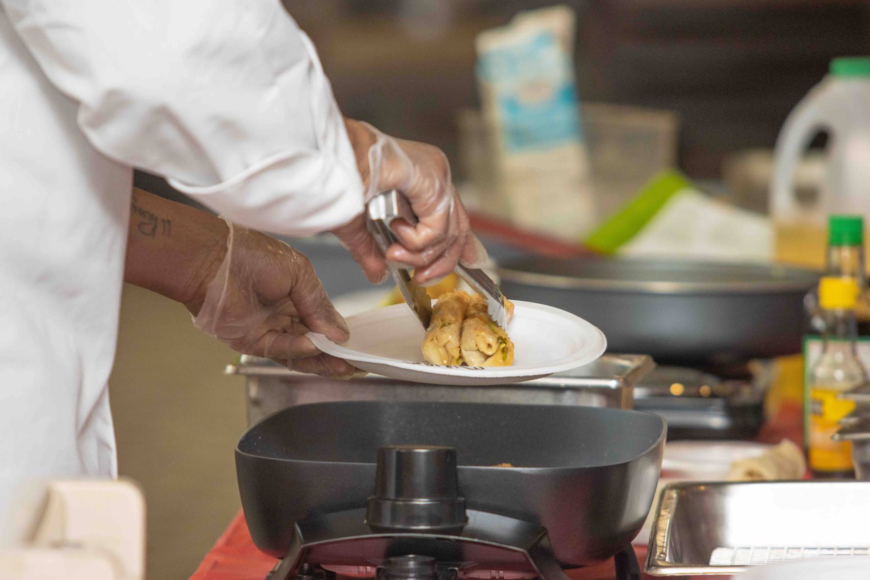 A chef dipping a lobster into a bowl.