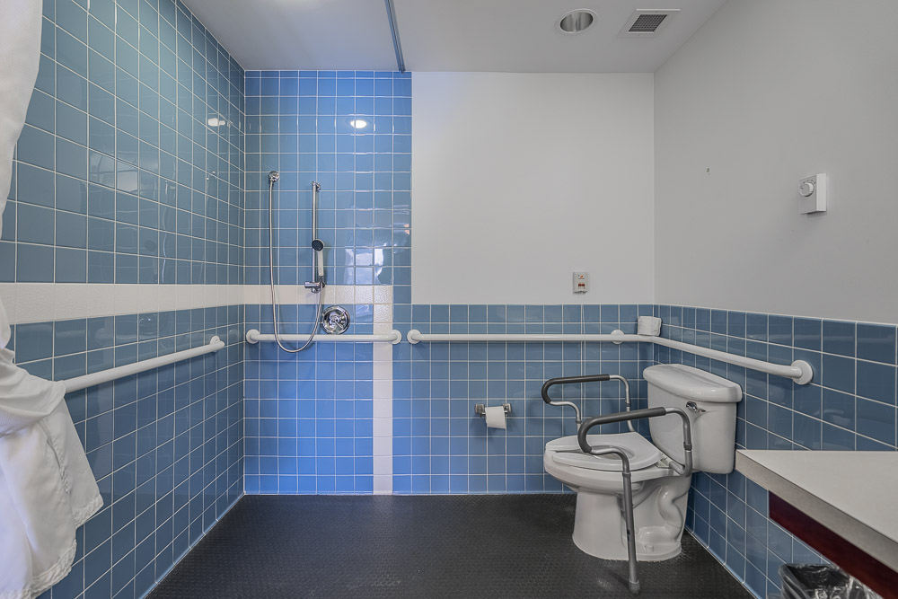 A bathroom with a special toilet to assist those undergoing physical rehabilitation.