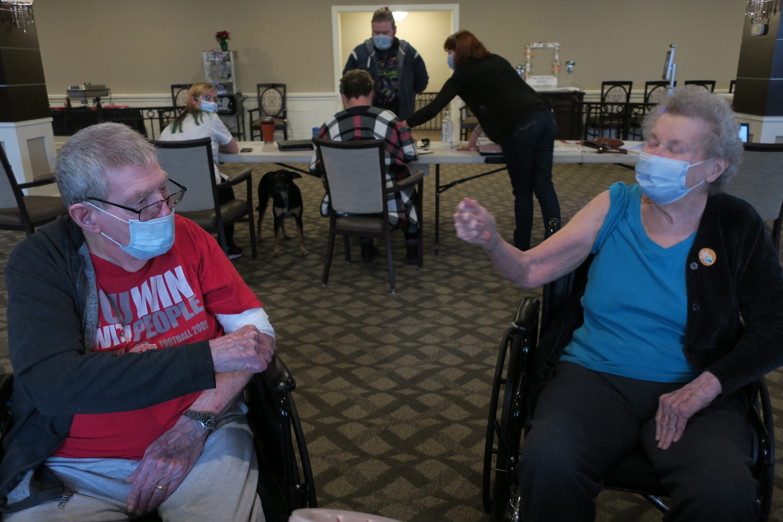 A woman and man, both in wheelchairs, greet each other after receiving vaccinations.