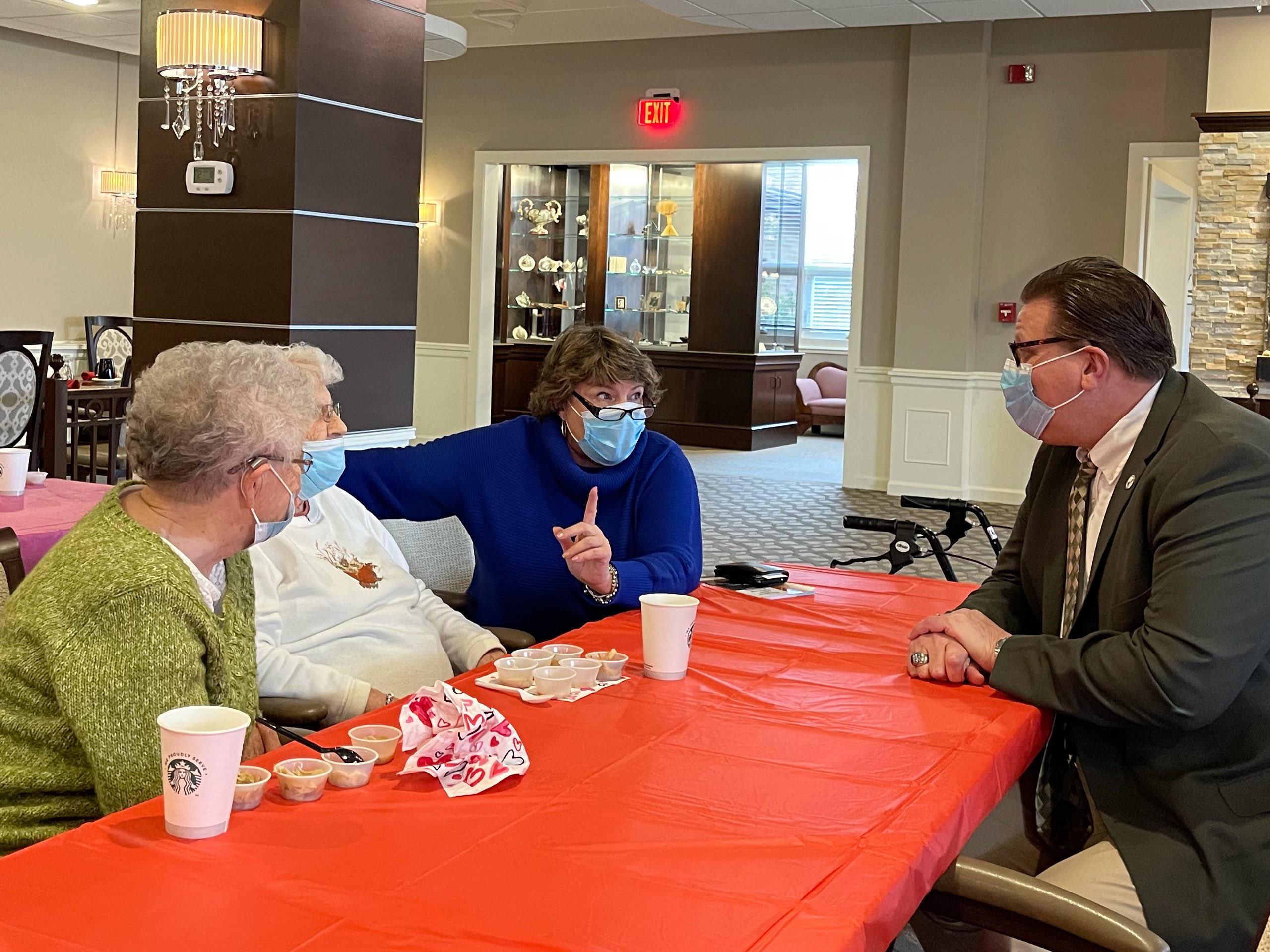 Mayor Matt Star sitting at a table with a red cloth across from two OESH staff members.