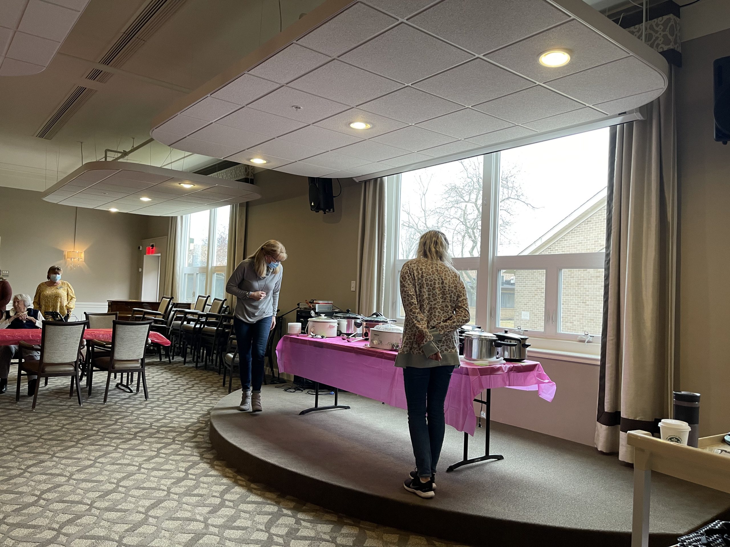 Two women on stage look at soup contest entries.
