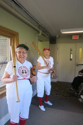 Two seniors in baseball uniforms holding wooden bats and smiling big for the camera!