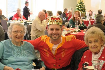 A man dressed as a prince posing with two OESH senior women.