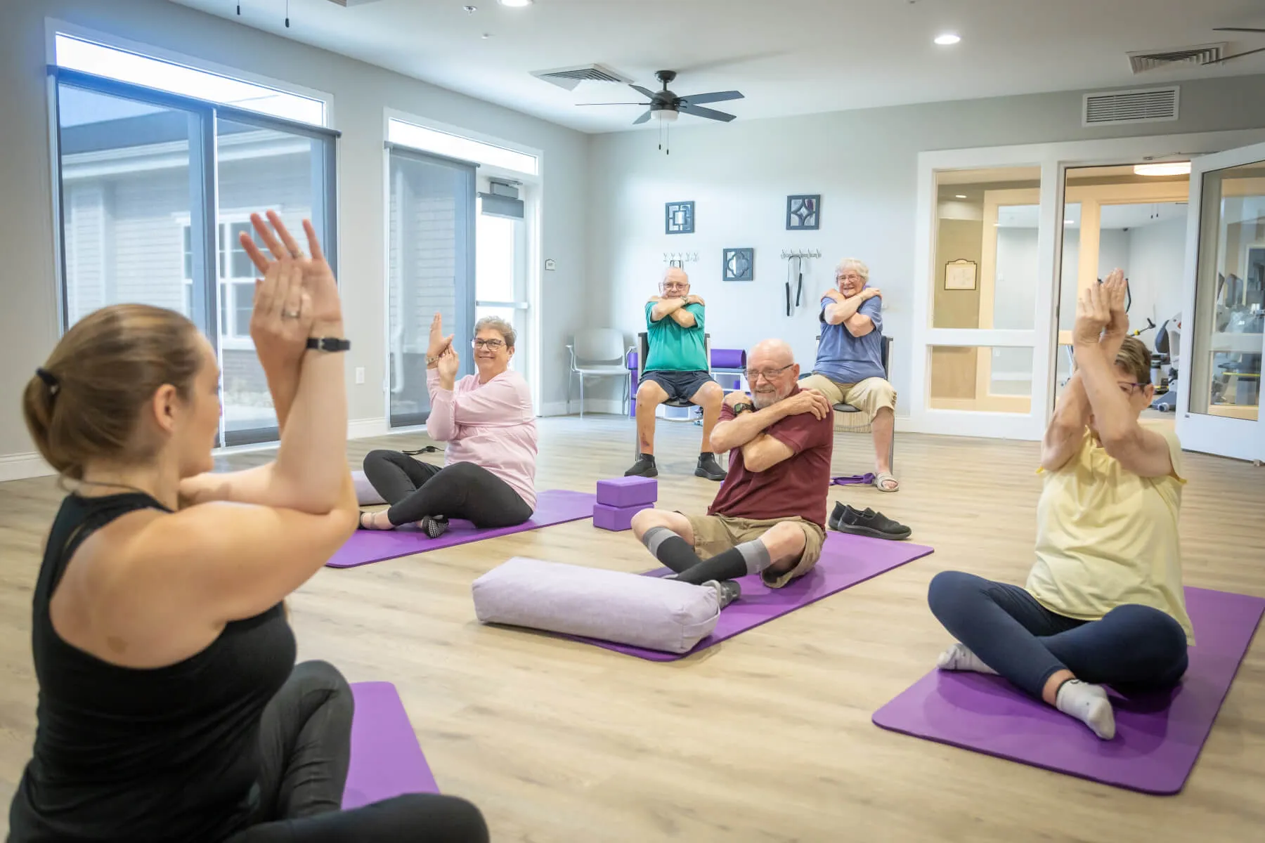 Five individuals experiencing the benefits of social interaction during a senior-focused yoga class.