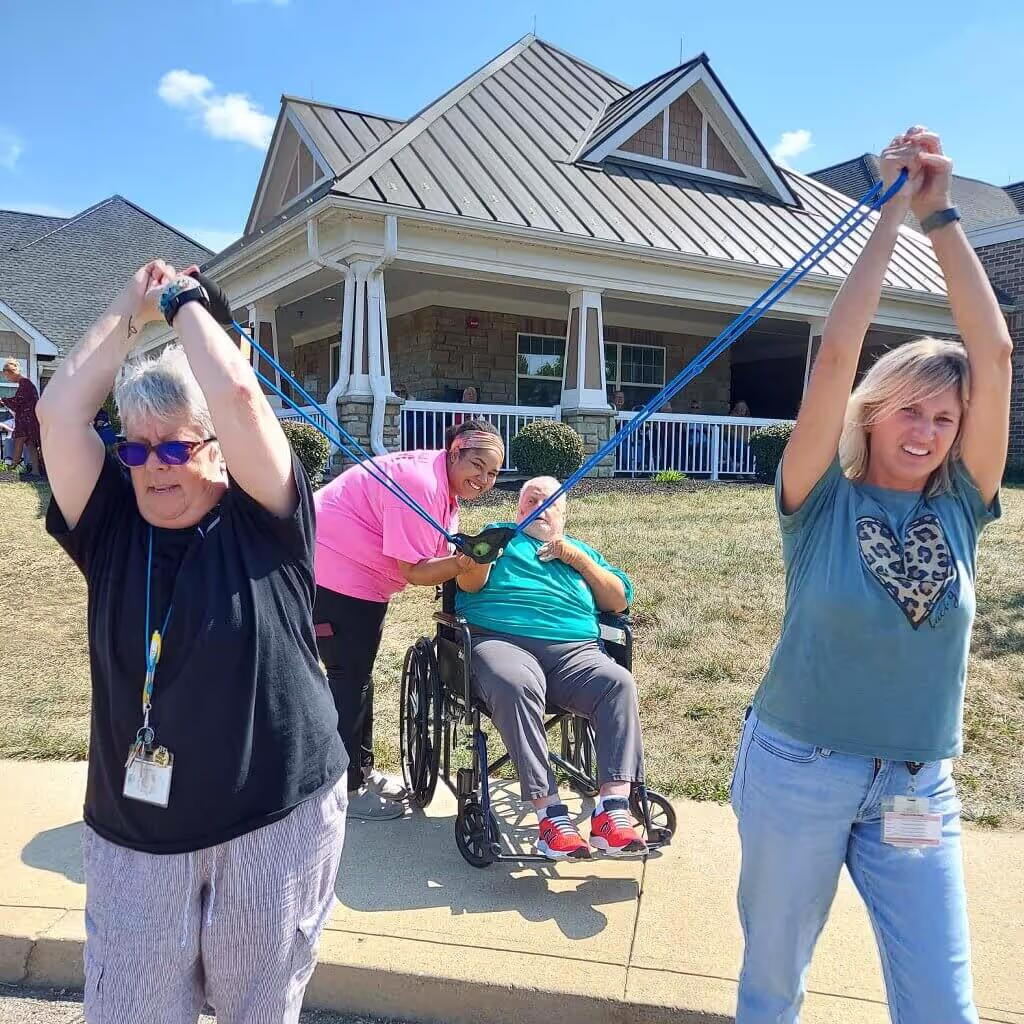 Staff and seniors socializing as they stretch a slingshot.