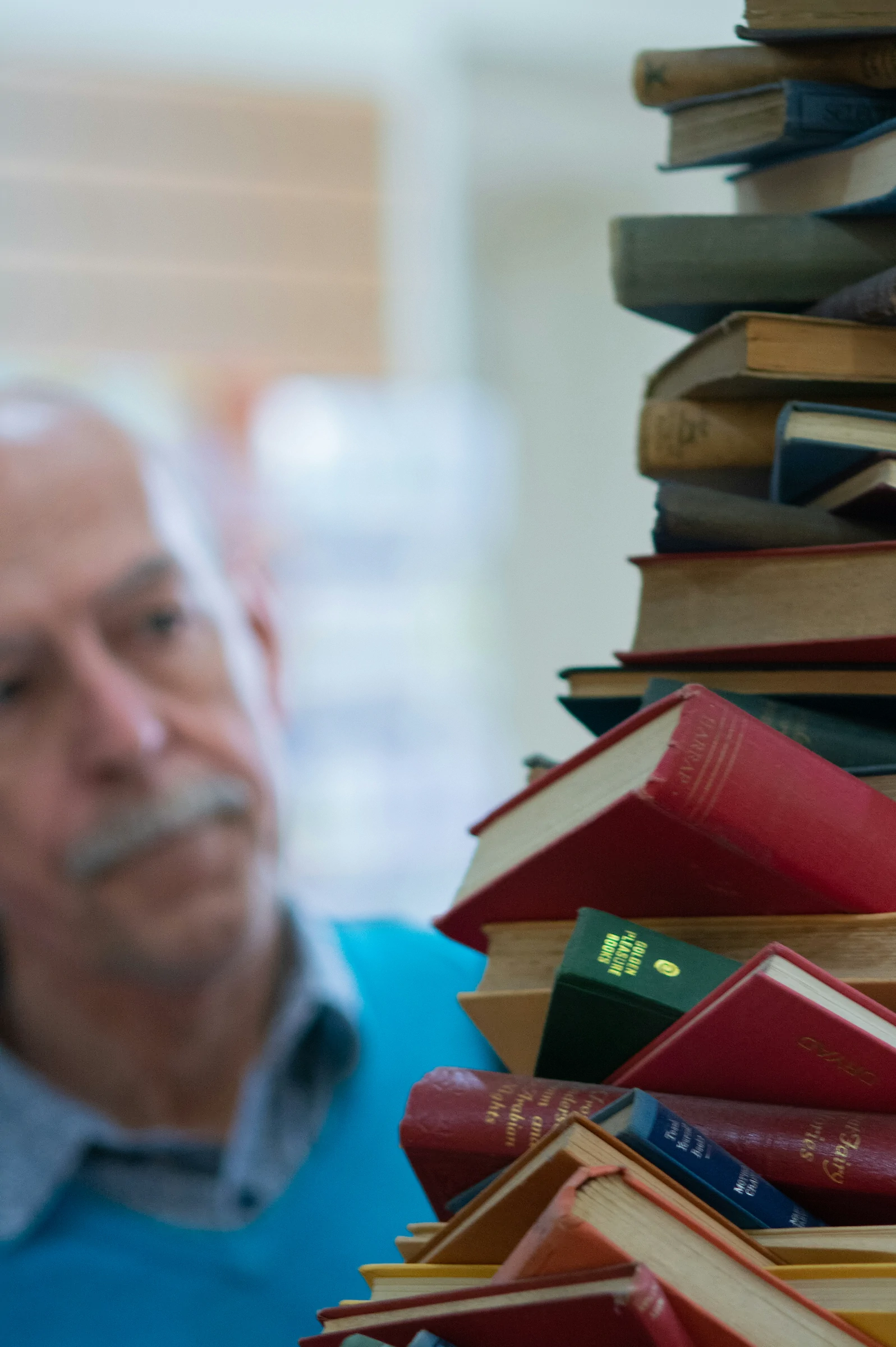 An elderly gentleman contemplating a large stack of books he must move.