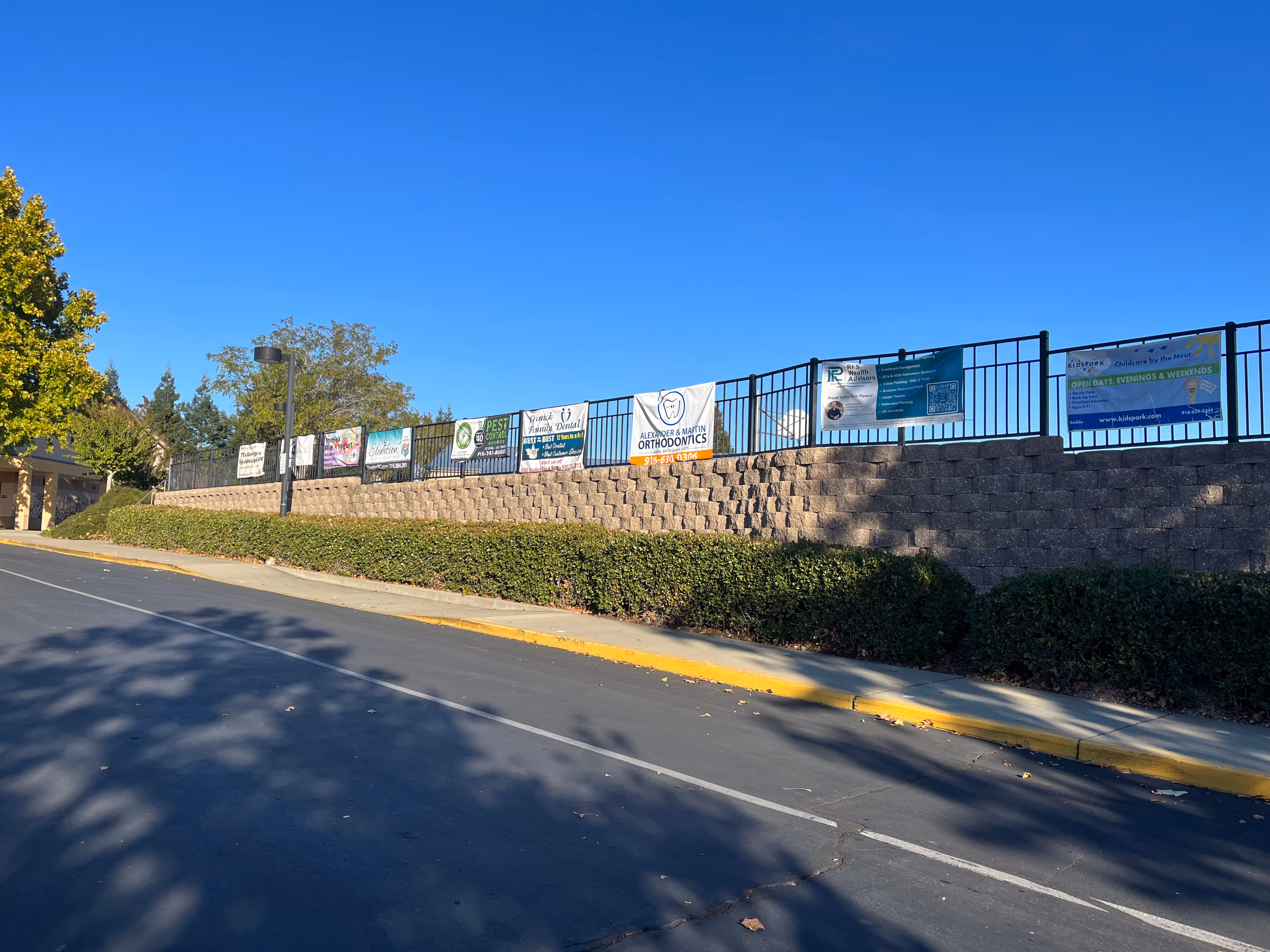 A school fence with sponsor banners tied to it.
