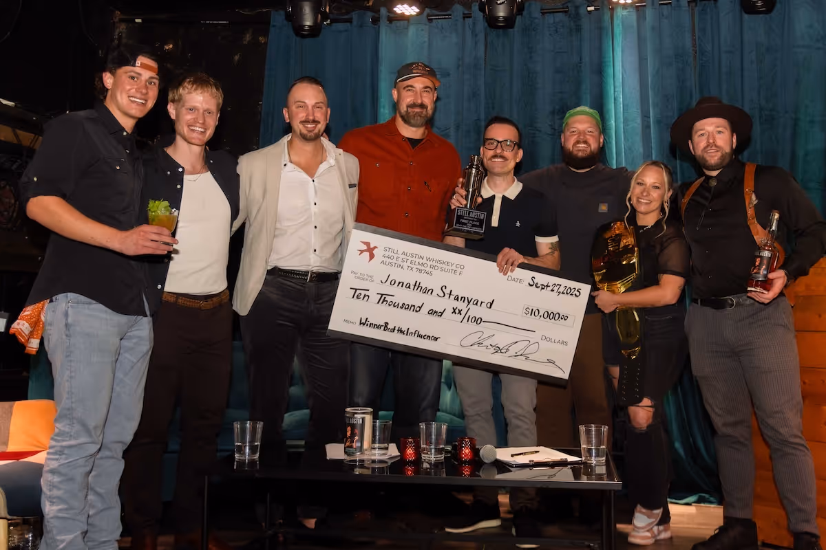 Beat The Influencer winners and judges celebrating on stage — Jonathan with the big check, Ashley rocking the championship belt, and the whole crew raising a glass.